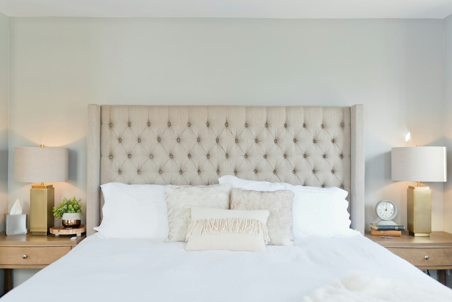Bedroom inspiration with a tufted linen headboard, timber bedside tables and warm lighting